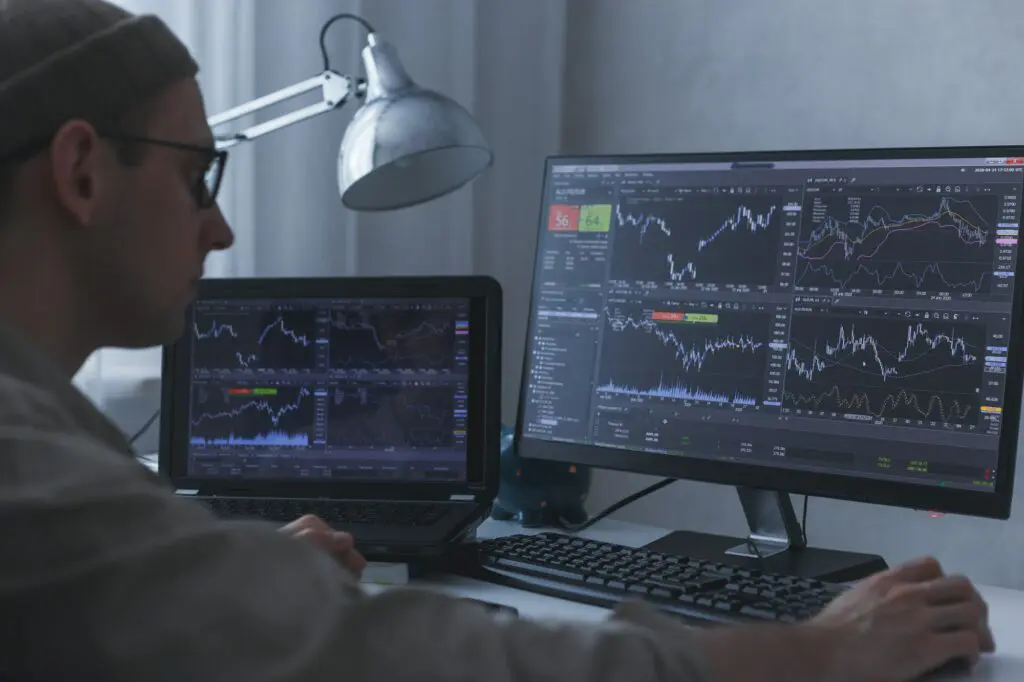 Thoughtful serious trader broker analyzing stock market graphs at pc and laptop
