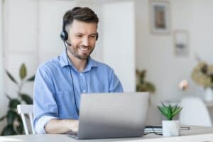 Call center operator at work. Male manager wearing headset and using laptop