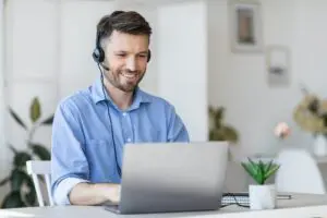 Call center operator at work. Male manager wearing headset and using laptop